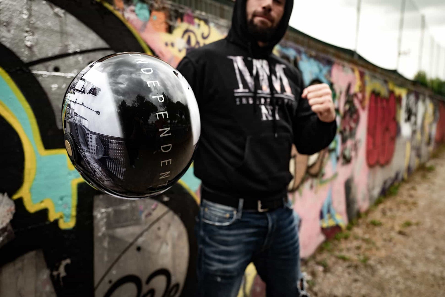 model wearing the mm independent branded sweatshirt holding the matching helmet